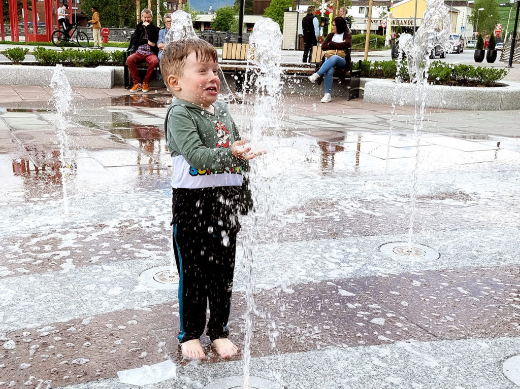 en gutt som står midt i en fontene