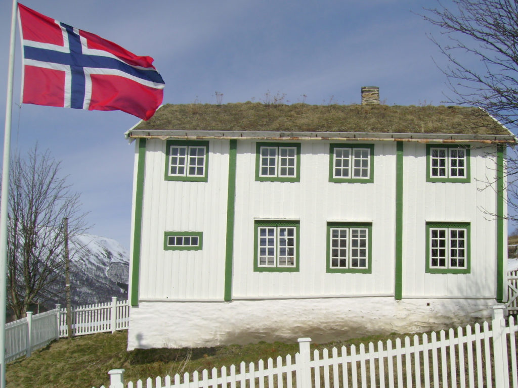 Bjørgan gård - et hvitt hus med norsk flagg på flaggstangen til venstre i bildet