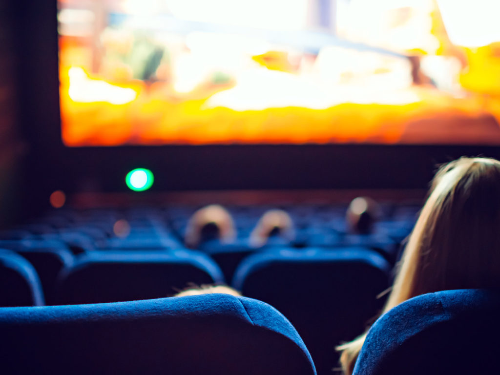 en kinosal med blå seter med bakhodet på noen som ser på kino